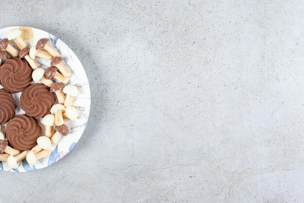 Печенье и шоколадные грибы на тарелке на мраморной поверхности