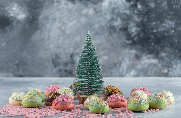 Cookies decorated with sprinkles around pine tree.