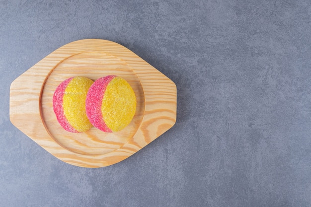 Печенье в виде персиков на деревянной тарелке на мраморном столе.