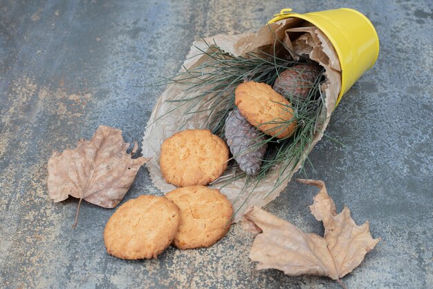 大理石のテーブルのバケツにクッキー、草、松ぼっくり。高品質の写真