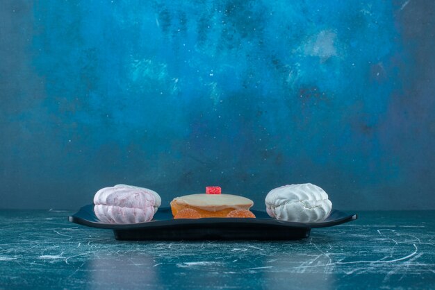 쿠키와 화이트 초콜릿 주위 marmelades 파란색 배경에 플래터에 케이크를 얹어. 고품질 사진