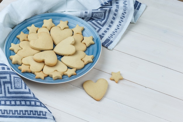 Cookies in a plate on wooden and kitchen towel background. high angle view.