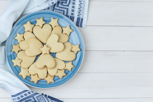 Cookies in a plate on wooden and kitchen towel background. top view.