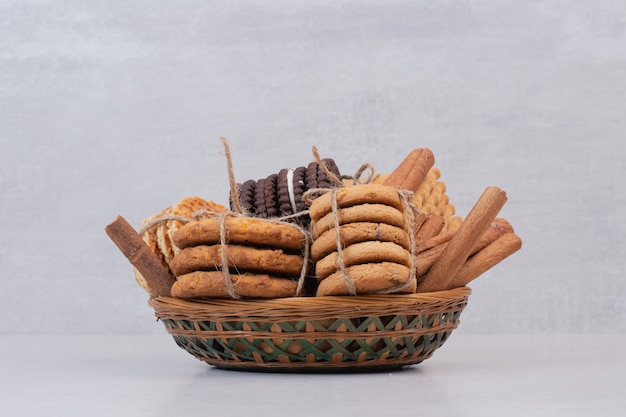 Cookies in rope with cinnamon sticks on white surface