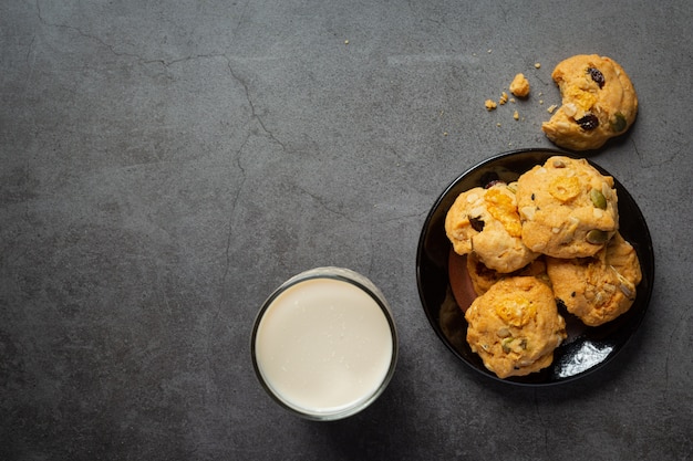 Cookies served with a glass of milk on dark floor