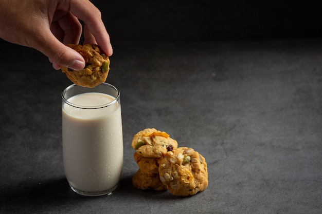 Cookies served with a glass of milk on dark floor