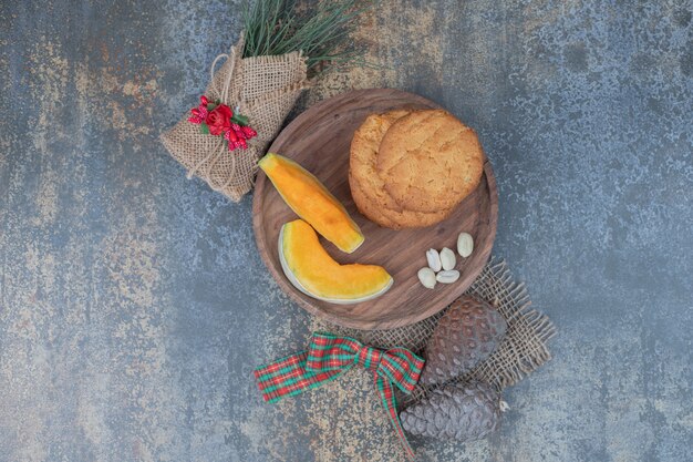 Cookies and slices of pumpkin on wooden plate decorated with ribbon. High quality photo