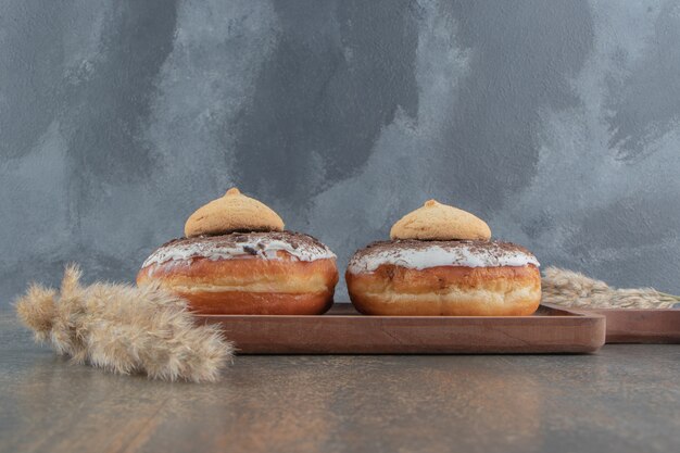 Cookies on top of donuts on wooden board on wooden table