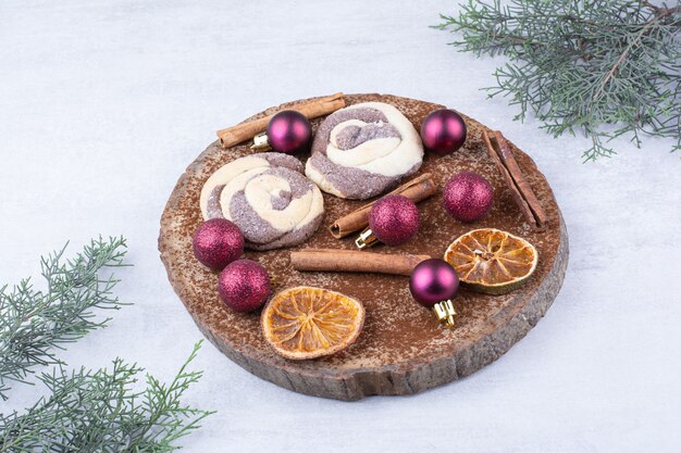 Cookies with baubles, cinnamons and orange slices on wood piece