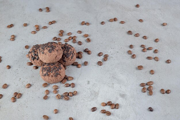 Cookies with chocolate chip topping and scattered coffee beans on marble table.