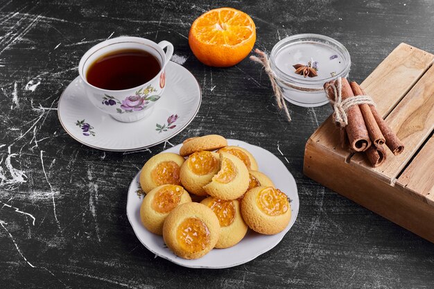 Cookies with orange jam served with a cup of tea. 