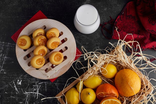 Foto gratuita biscotti con marmellata di arance serviti con un bicchiere di latte, vista dall'alto.