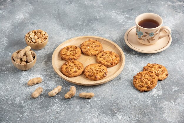 Cookies with organic peanuts and honey on wooden board with cup of tea. 