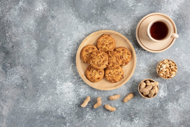 Cookies with organic peanuts and honey on wooden board with cup of tea. 