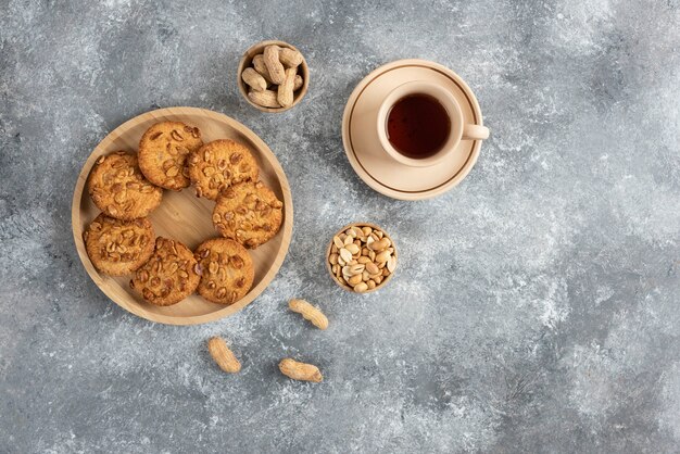 Cookies with organic peanuts and honey on wooden board with cup of tea. 