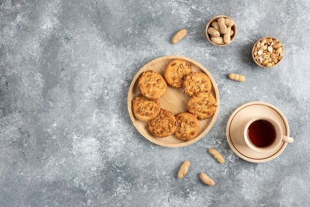 Печенье с органическим арахисом и медом на деревянной доске с чашкой чая.
