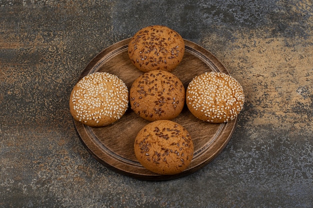 Cookies with sesame seeds and chocolate pieces on wooden board. 