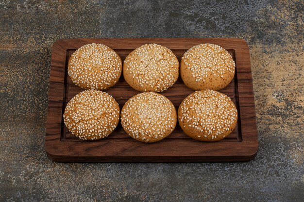 Cookies with sesame seeds on a wooden plate. 