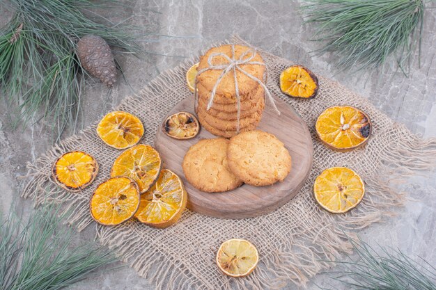 周りに乾燥したオレンジスライスが付いている木の板のクッキー。