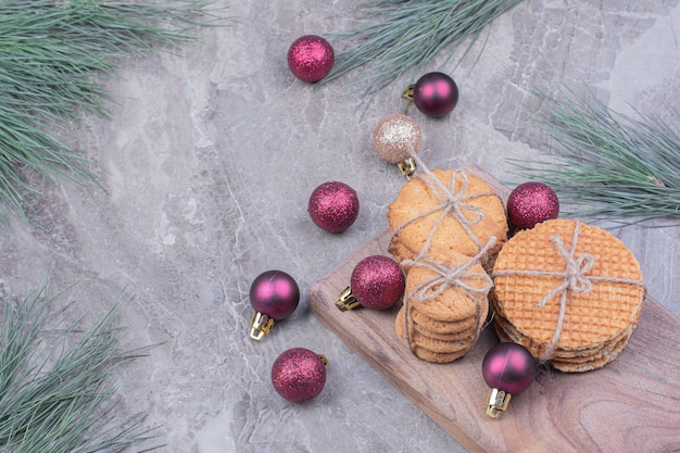 Cookies on a wooden board with red glitter christmas balls around