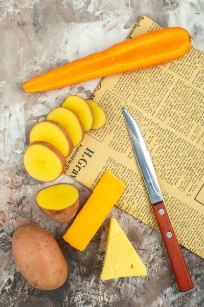 古い新聞で様々な野菜と2種類のチーズナイフを使った料理の背景