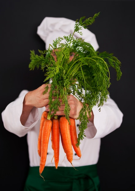 Cooking chef holding bunch of fresh carrots