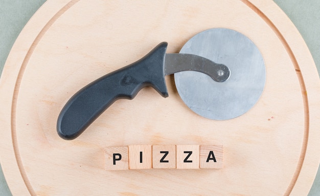 Foto gratuita concetto di cucina con blocchi di legno con parole, vista dall'alto di tagliapizza.