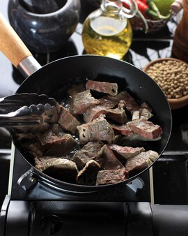 調理​プロセス​牛肉​の​肺​を​より​少ない​油​で​黒い​鍋​で​揚げる