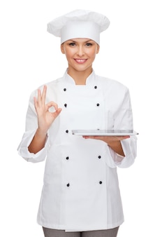Cooking, technology and food concept - smiling female chef, cook or baker with tablet pc computer and ok sign