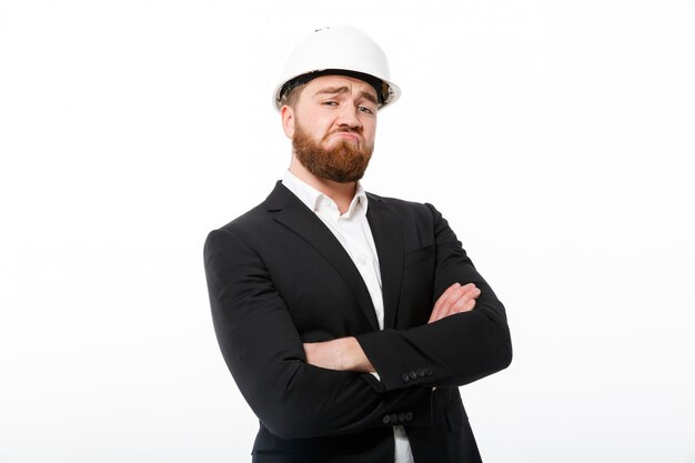 Cool bearded business man in protective helmet holding crossed arms