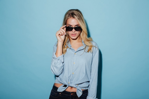 Cool blonde woman in shirt and sunglasses looking at camera