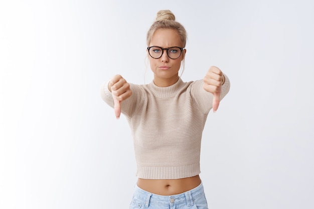 Not cool. Displeased angry and upset serious-looking fed up girlfriend breaking-up with cruel disresprecful boyfriend showing thumbs down smirking in dismay frowning posing over white wall