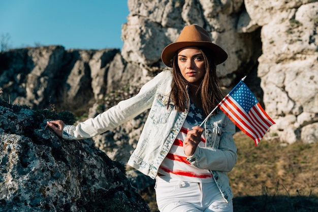 Cool female holding US flag standing on rocks