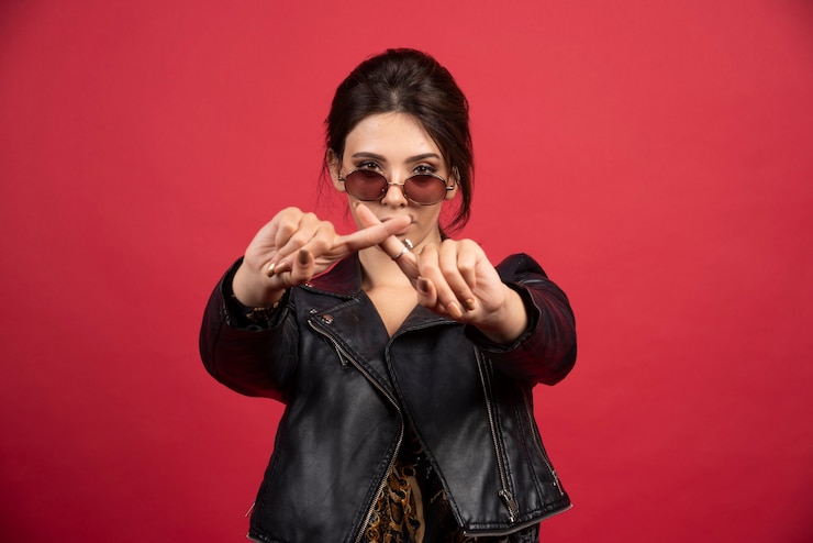 मुफ़्त फोटो cool girl in black leather jacket crossing hands or fingers to stop something. 