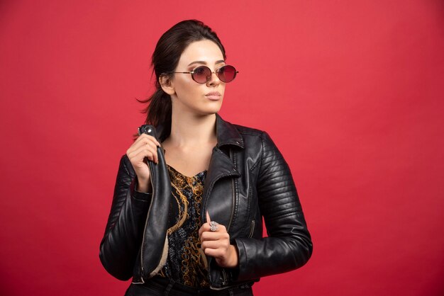 cool girl in black leather jacket and sunglasses looks strict and demanding. 