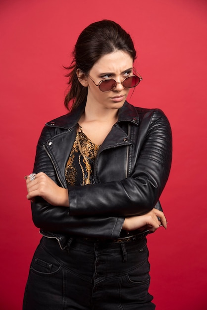 cool girl in black leather jacket and sunglasses looks strict and demanding. 