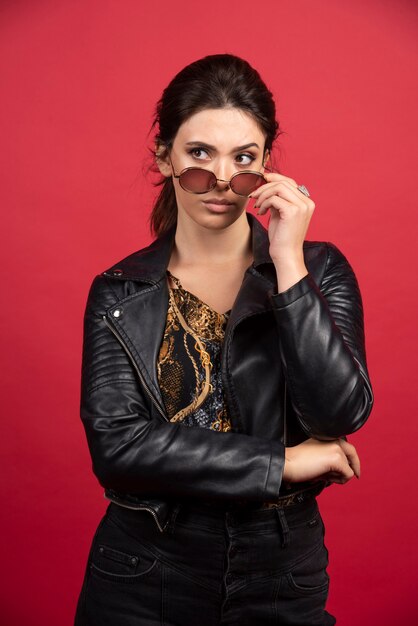cool girl in black leather jacket taking out her sunglasses and smiling. 