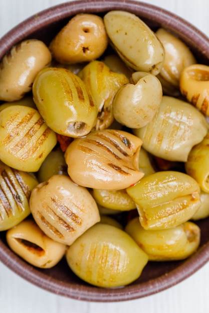 Cool green olives in a clay bowl on white. close-up.