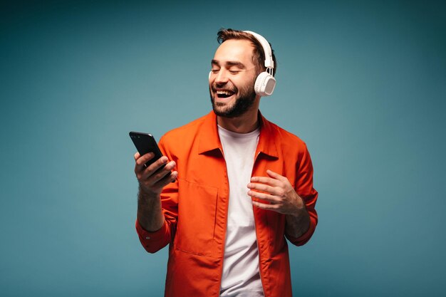 Cool guy chatting via phone and enjoys music in headphones