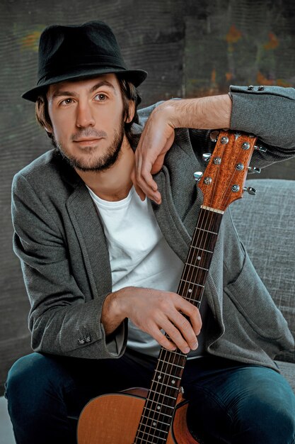 Cool guy sitting with guitar on gray space