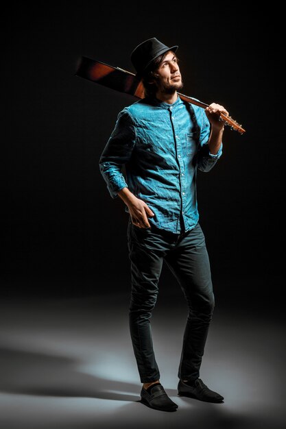 Cool guy standing with guitar on dark space