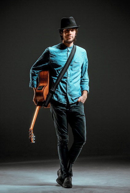 Free photo cool guy standing with guitar on dark