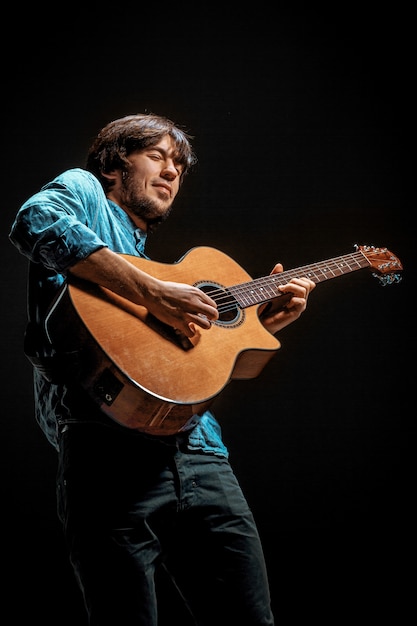 Cool guy standing with guitar on dark