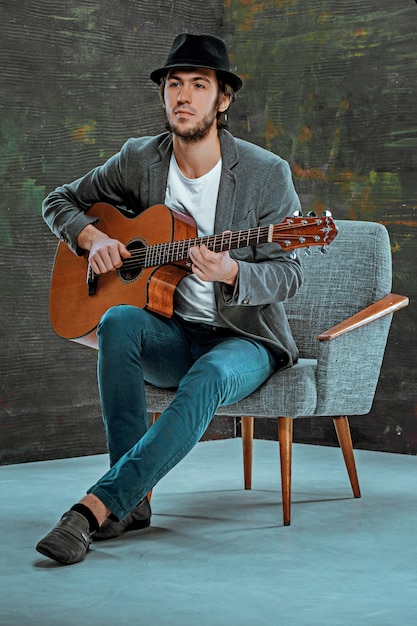 Cool guy with hat playing guitar on gray