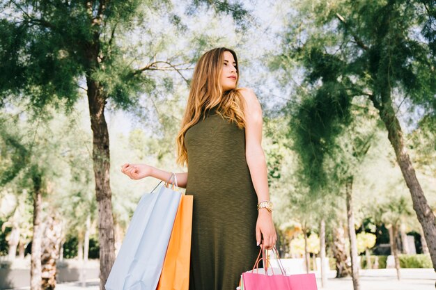 Cool model posing in the nature with shopping bags