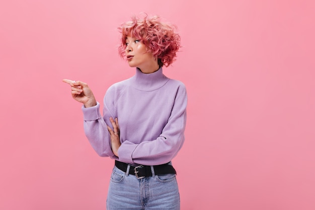 Free photo cool pink-haired woman pointing to left on place for text