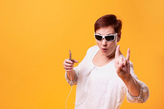 Cool senior woman listening rock music