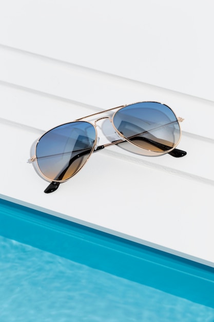 Классные солнцезащитные очки рядом с небольшим бассейном