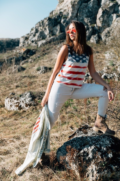 Free photo cool trendy woman standing on stone in sunlight