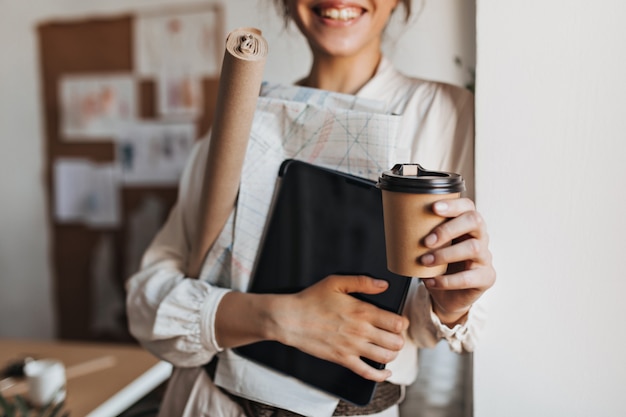 クールな女性は、ドキュメントとコーヒーカップを保持します